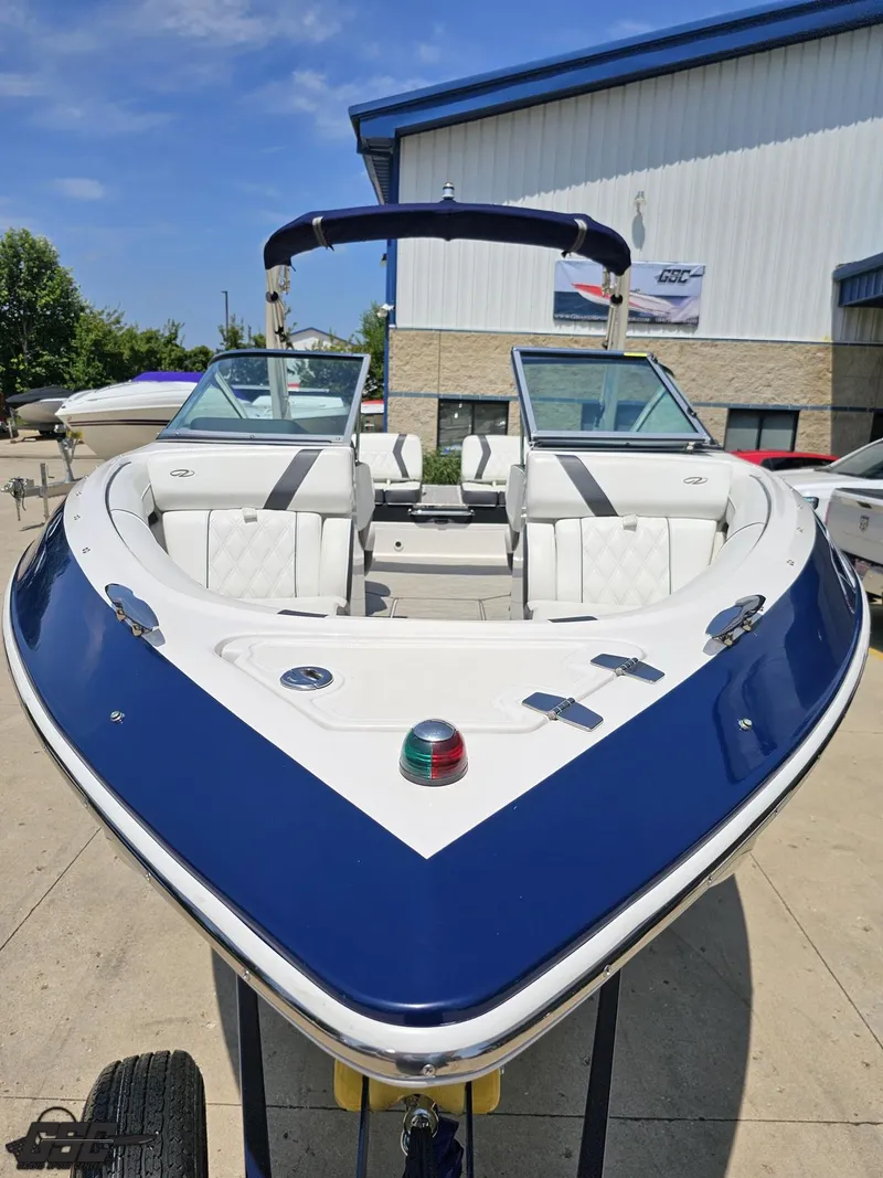Slide: The Image of 2018 Regal 2300 Bowrider boat with blue and white design, parked outdoors. - 14