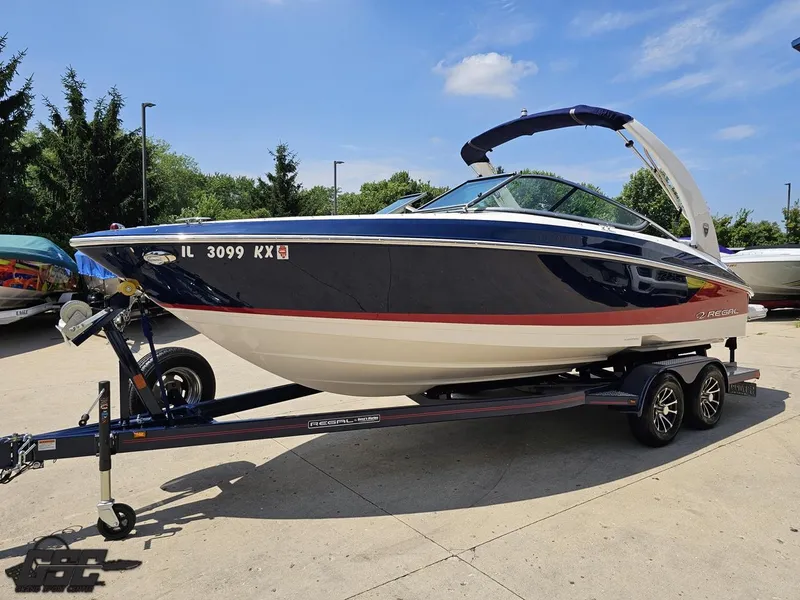Slide: The Image of 2018 Regal 2300 Bowrider boat on trailer, parked outdoors under blue sky. - 17
