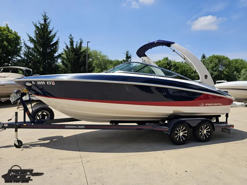 Slide: The Image of 2018 Regal 2300 Bowrider boat on trailer, parked outdoors under clear sky. - 18