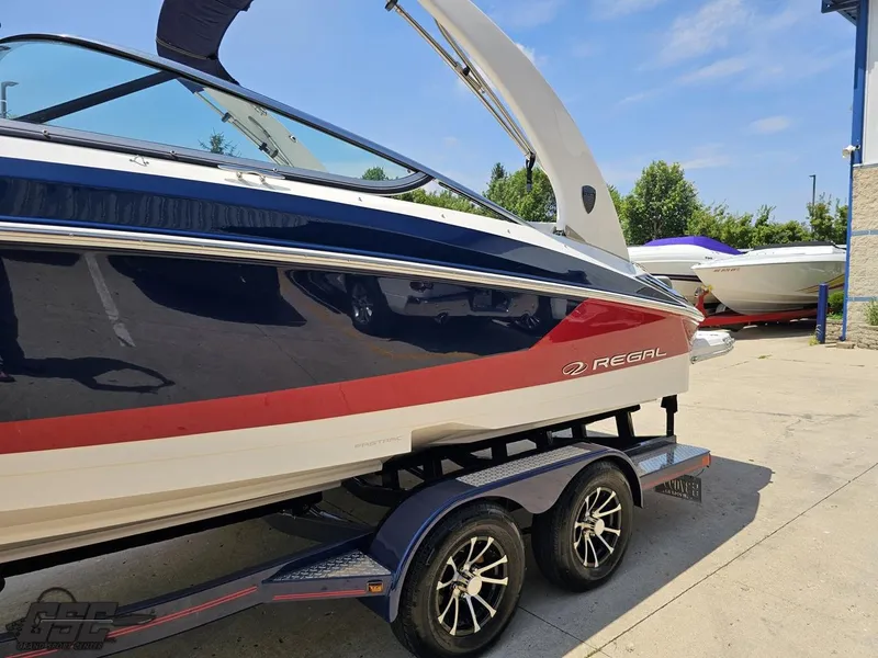 Slide: The Image of 2018 Regal 2300 Bowrider boat on trailer, blue and red design, parked outdoors. - 22