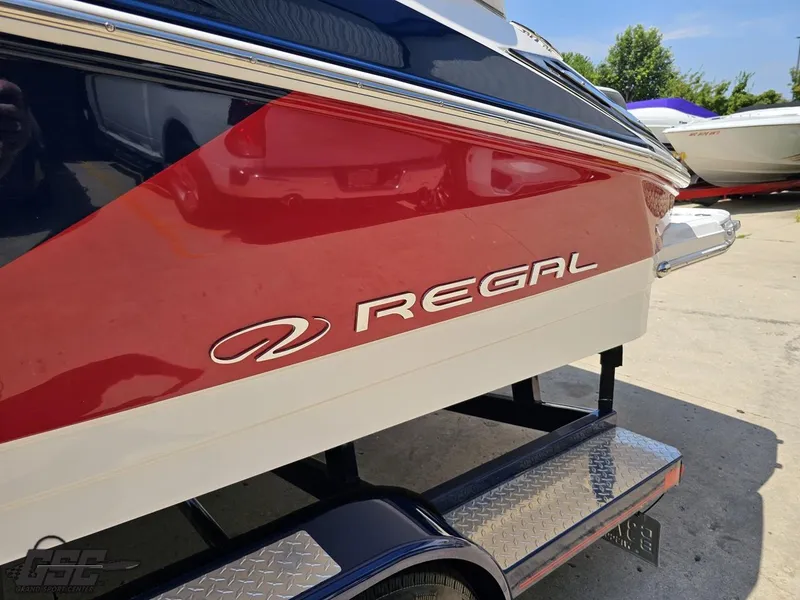 Slide: The Image of 2018 Regal 2300 Bowrider boat on trailer, featuring red and white design. - 24