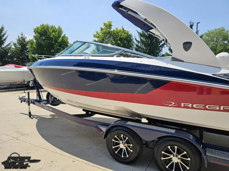 Slide: The Image of 2018 Regal 2300 Bowrider boat on trailer, blue and red design, parked outdoors. - 26