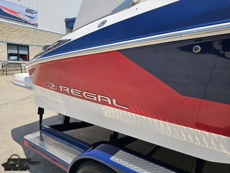 Slide: The Image of 2018 Regal 2300 Bowrider boat with red and blue exterior on a trailer. - 5