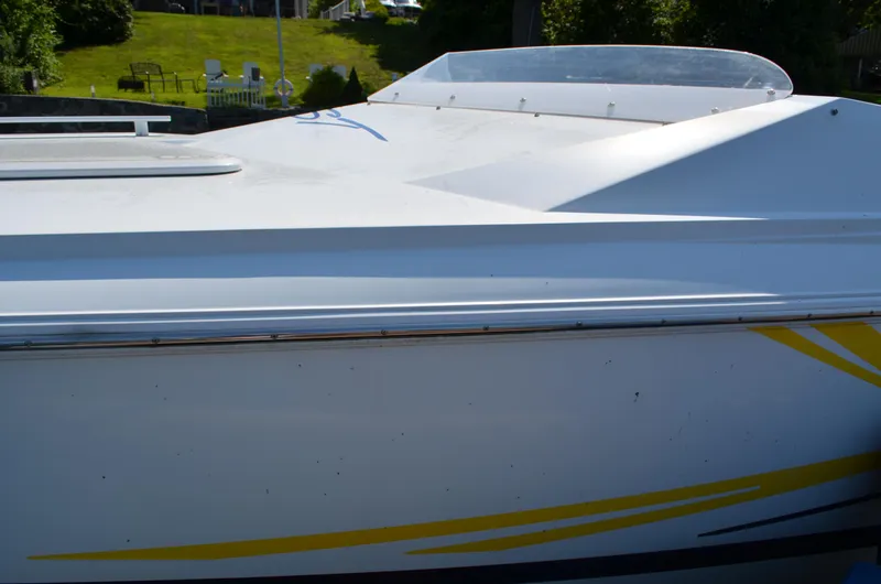 Slide: The Image of 2008 Baja 26 Outlaw boat with sleek white and yellow design, docked outdoors. - 3