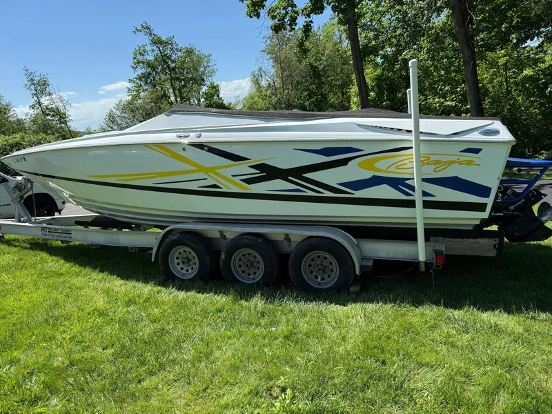 Slide: The Image of 2008 Baja 26 Outlaw boat on trailer, parked on grass, with vibrant graphics. - 35