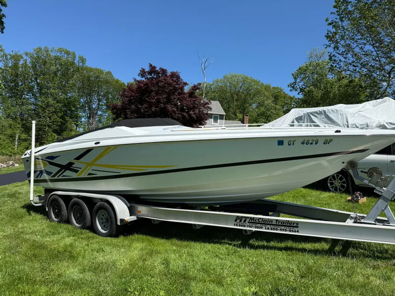 Slide: The Image of 2008 Baja 26 Outlaw boat on trailer, parked on grass with trees in background. - 36