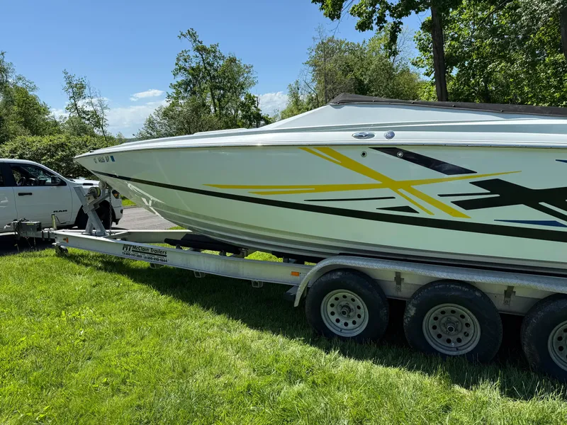 Slide: The Image of 2008 Baja 26 Outlaw boat on trailer, parked on grass, with vibrant graphics. - 37