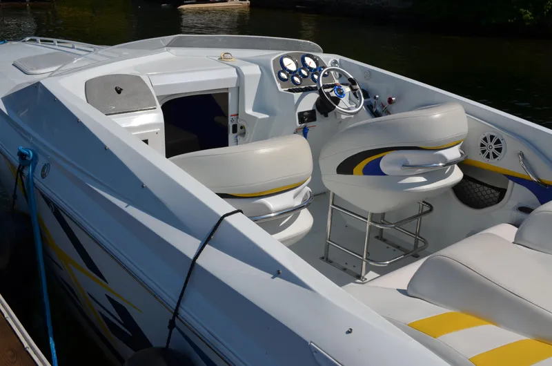 Slide: The Image of 2008 Baja 26 Outlaw boat interior with sleek white and yellow seating, docked on water. - 8
