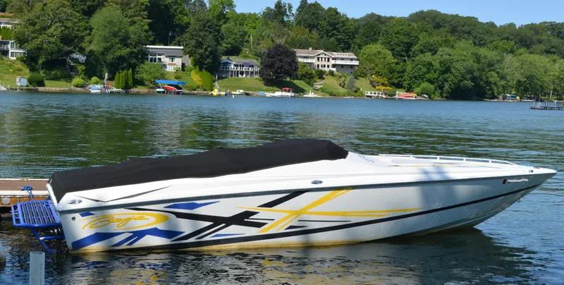 The Image of 2008 Baja 26 Outlaw boat docked on a scenic lake with lush greenery. - 0