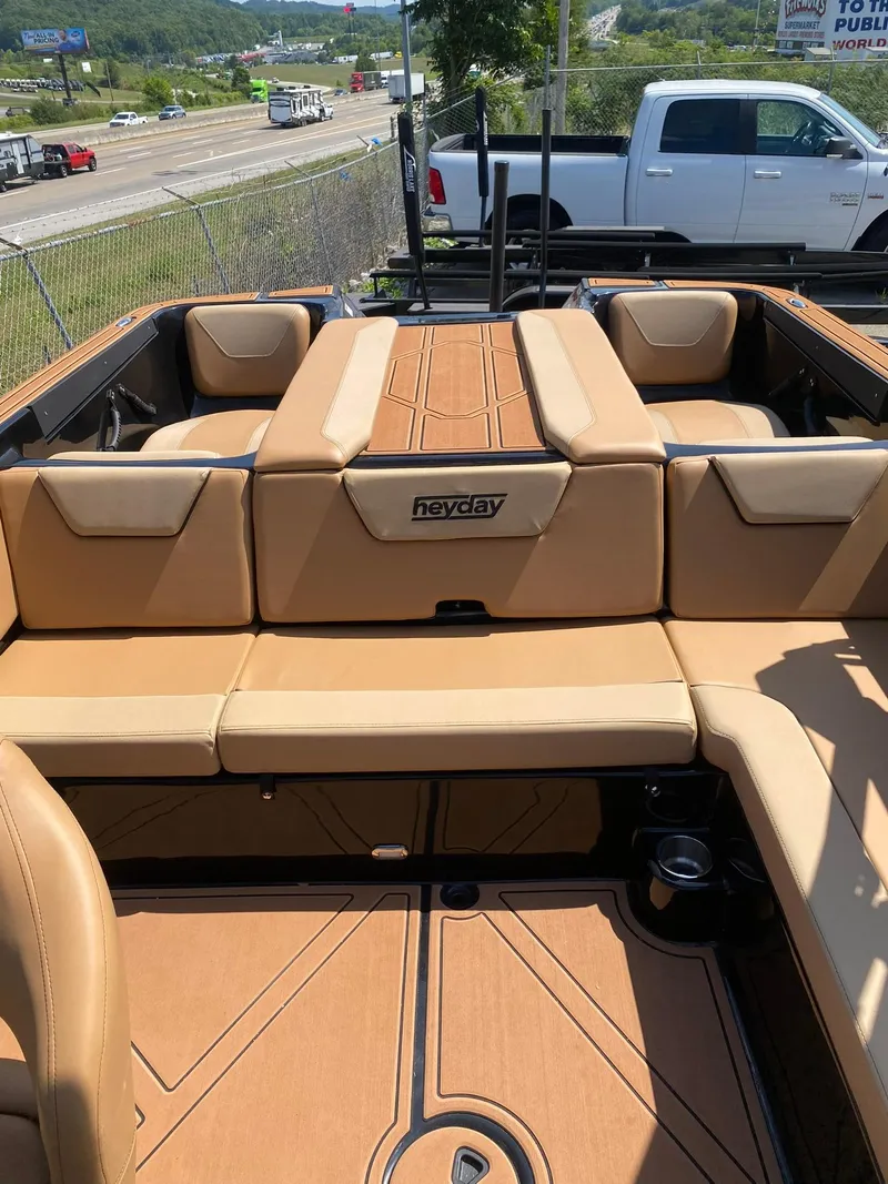 Slide: The Image of 2025 Heyday WT-2DC boat interior with tan seating and logo, parked near highway. - 15