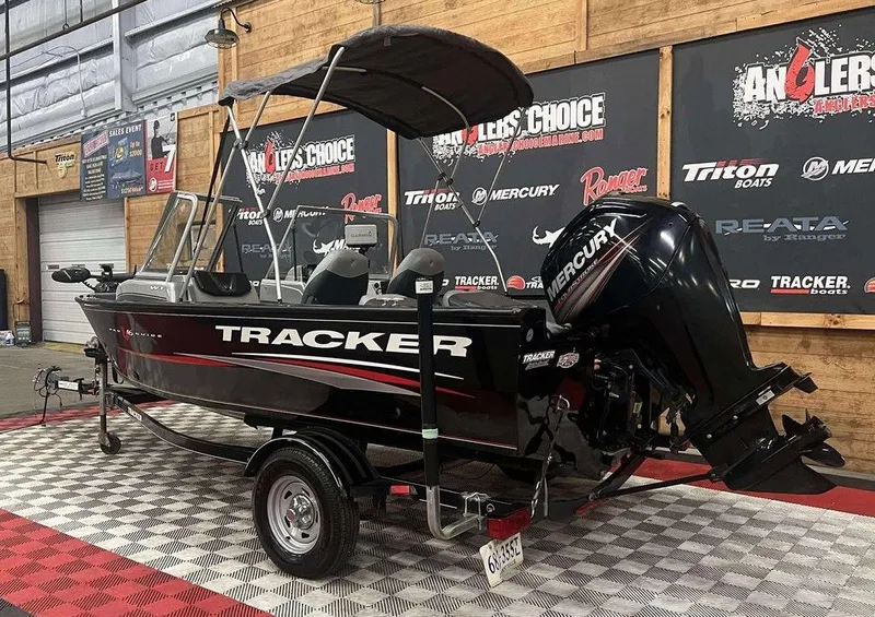 Slide: The Image of 2016 Tracker Pro Guide V-16 WT boat with Mercury engine on display indoors. - 3