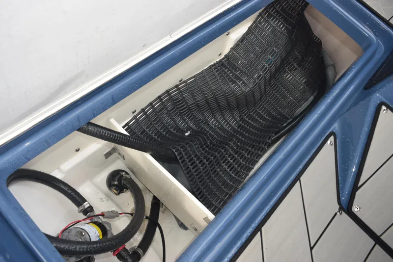 Slide: The Image of 2023 Yamaha Boats 255XD storage compartment with hoses and netting. - 19