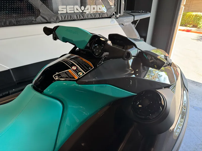 Slide: The Image of 2025 Sea-Doo GTR 230 jet ski with teal seat and handlebars in a showroom. - 7