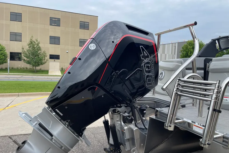 Slide: The Image of 2024 Manitou LX 25 RFXW boat with powerful outboard motor, docked near a modern building. - 10