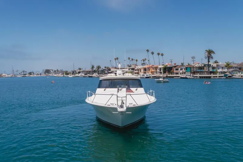 Slide: The Image of 2008 Viking 52 Sport Coupe yacht cruising in a scenic harbor with waterfront homes. - 29