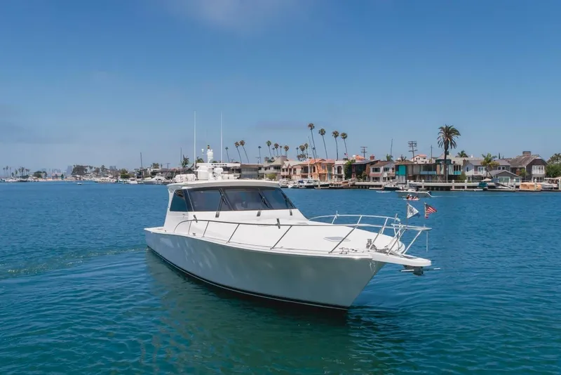 Slide: The Image of 2008 Viking 52 Sport Coupe yacht cruising near coastal homes under clear blue skies. - 31