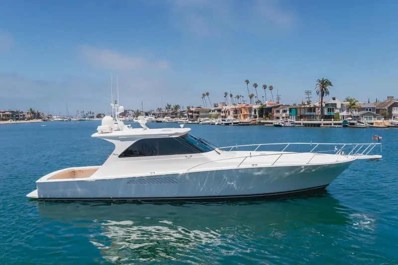 Slide: The Image of 2008 Viking 52 Sport Coupe yacht cruising in a scenic coastal area. - 32