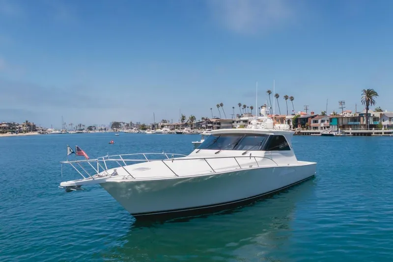 Slide: The Image of 2008 Viking 52 Sport Coupe yacht cruising in a scenic coastal harbor. - 43