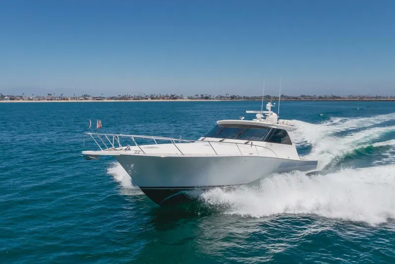 Slide: The Image of 2008 Viking 52 Sport Coupe cruising on open water, clear blue sky. - 45
