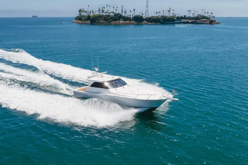 Slide: The Image of 2008 Viking 52 Sport Coupe cruising on blue ocean near a small island. - 47