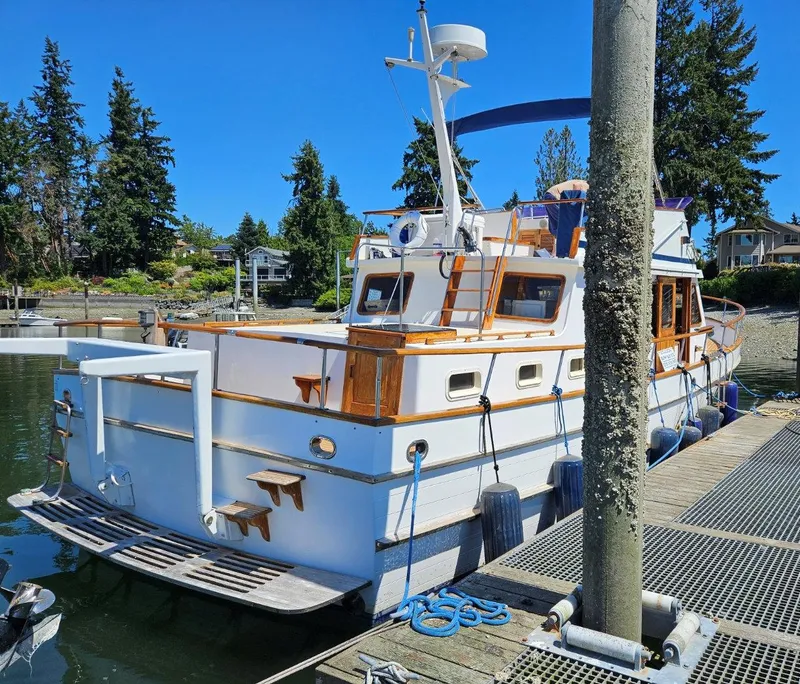 The Image of 1981 Ocean Double Cabin Trawler docked at marina, surrounded by trees and clear blue sky. - 0