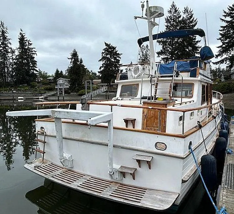 Slide: The Image of 1981 Ocean Double Cabin Trawler docked, featuring wooden accents and blue canopy. - 12