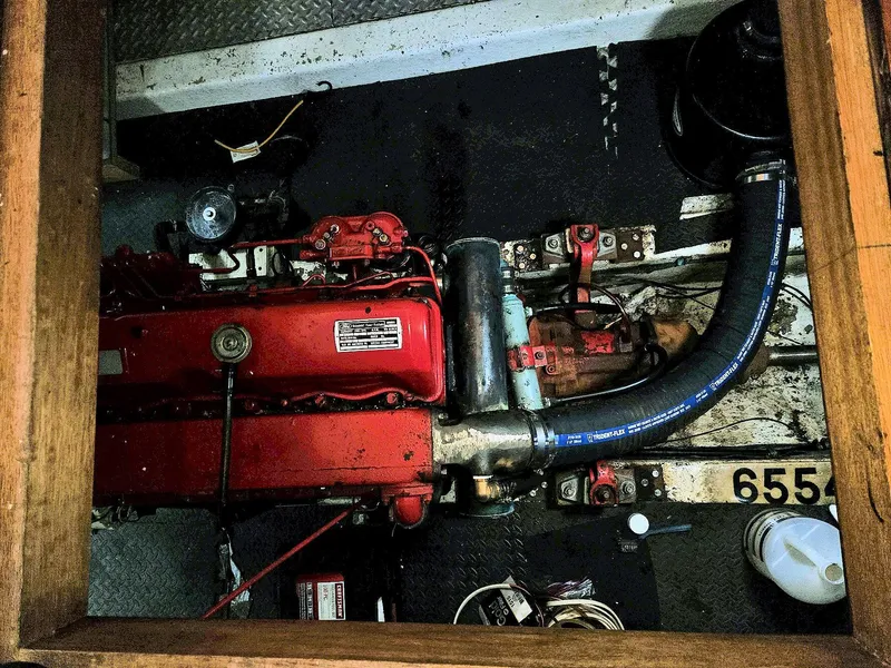 Slide: The Image of Engine compartment of a 1981 Ocean Double Cabin Trawler, featuring a red engine and hoses. - 14