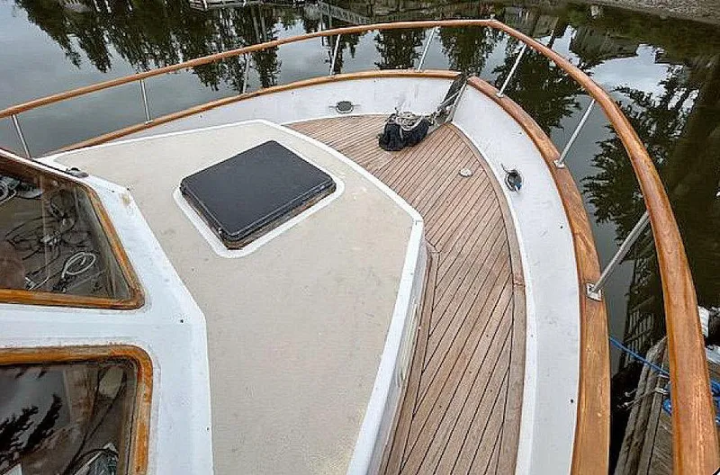 Slide: The Image of 1981 Ocean Double Cabin Trawler deck with wooden railings and hatch, docked by calm water. - 21