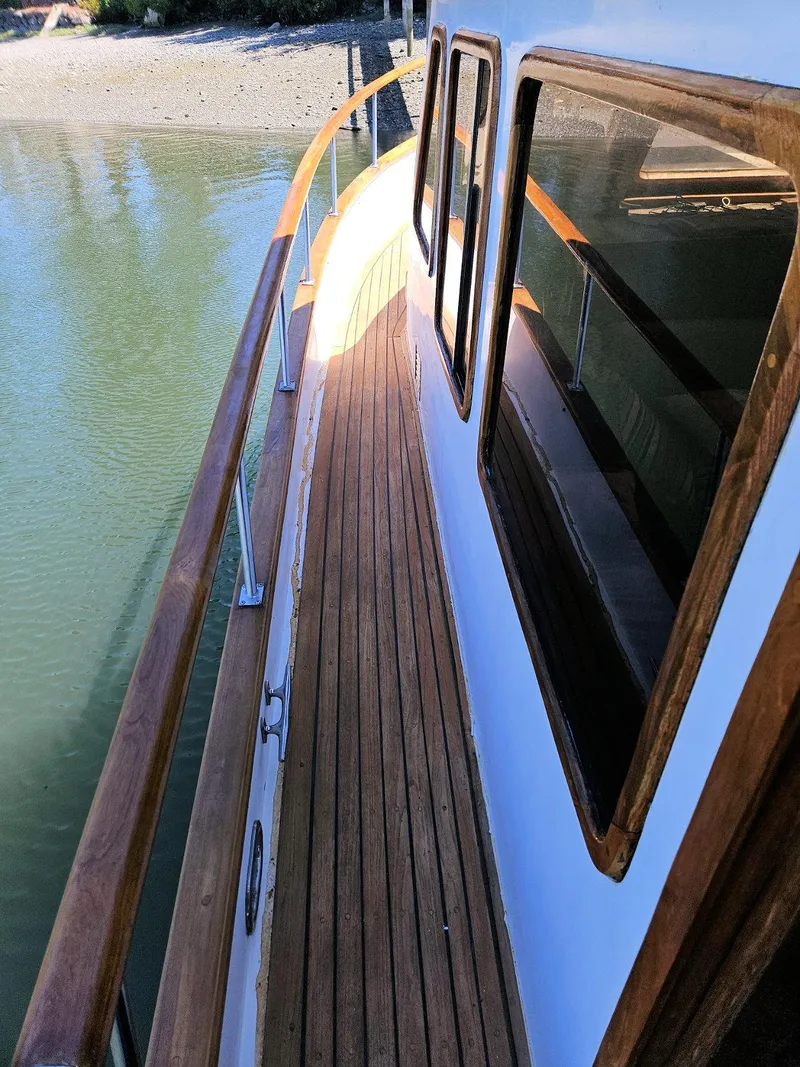 Slide: The Image of 1981 Ocean Double Cabin Trawler with wooden deck and railing, docked by calm water. - 22
