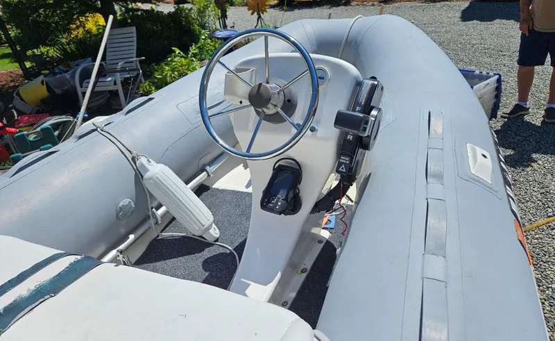 Slide: The Image of Inflatable boat with steering wheel and controls, parked on gravel. - 27