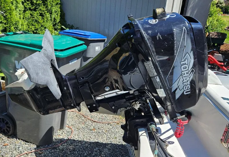 Slide: The Image of Tohatsu outboard motor on a 1981 Ocean Double Cabin Trawler, parked near recycling bins. - 28