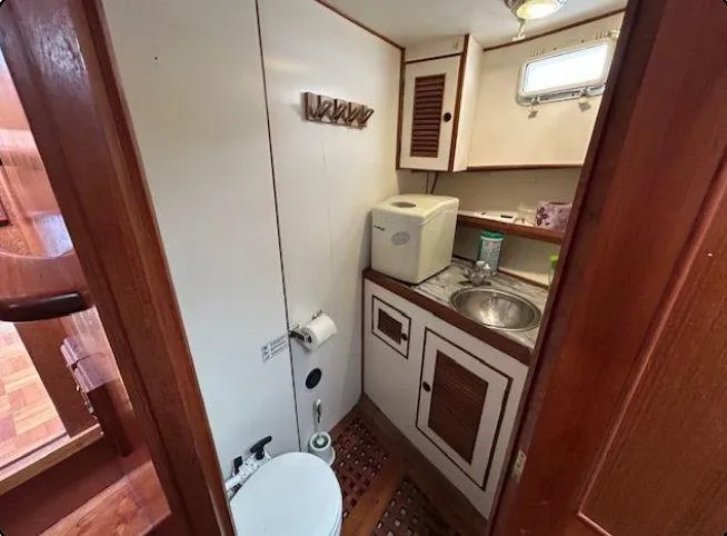 Slide: The Image of 1981 Ocean Double Cabin Trawler bathroom with sink, toilet, and storage cabinets. - 8