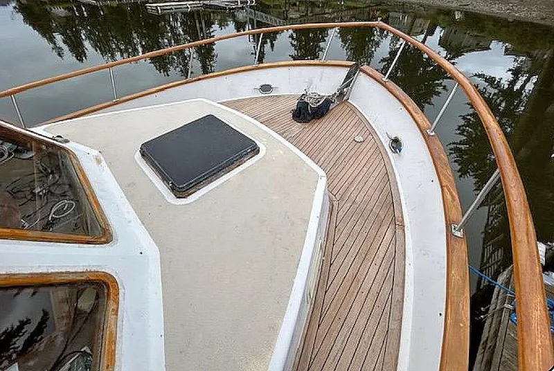 Slide: The Image of 1981 Ocean Double Cabin Trawler deck with wooden railings and hatch, docked by calm water. - 9