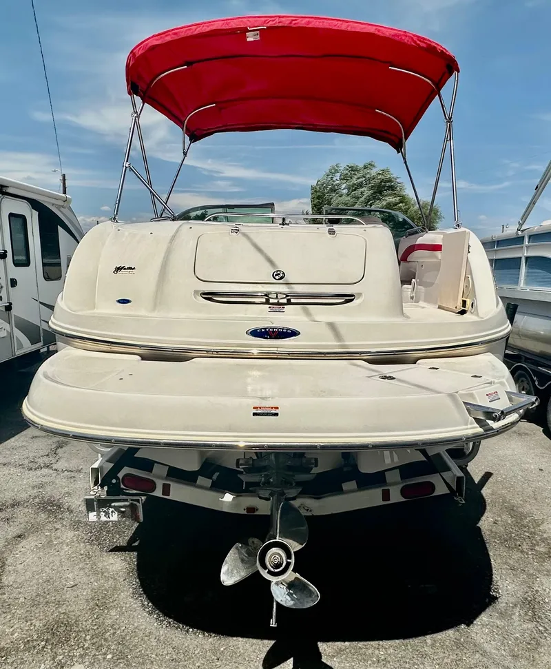 Slide: The Image of 2003 Chaparral 223 Sunesta boat with red canopy, rear view, parked outdoors. - 3