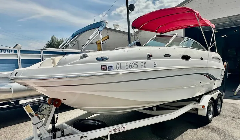 Slide: The Image of 2003 Chaparral 223 Sunesta boat with red canopy on trailer, parked outdoors. - 5