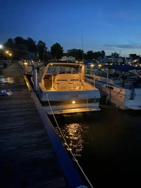 Slide: The Image of 1988 Trojan International boat docked at night, softly illuminated, with a serene waterfront backdrop. - 4