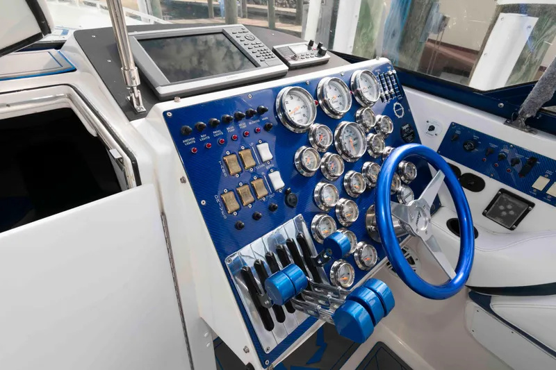 Slide: The Image of Control panel of a 1999 Fountain 47 Lightning boat with gauges and blue steering wheel. - 13