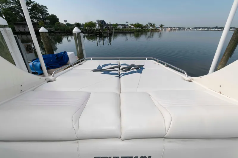Slide: The Image of 1999 Fountain 47 Lightning boat with white seating, docked by a calm waterfront. - 16