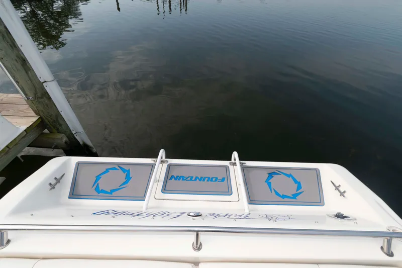 Slide: The Image of 1999 Fountain 47 Lightning boat stern view at dock, featuring logo and calm water. - 17