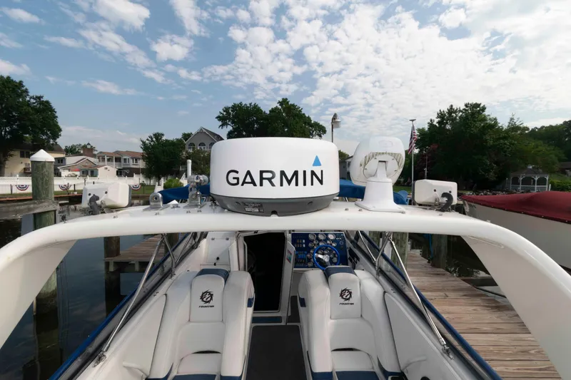 Slide: The Image of 1999 Fountain 47 Lightning boat with Garmin equipment, docked near waterfront homes under a cloudy sky. - 18
