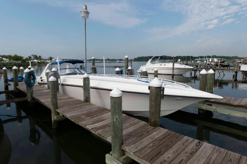 Slide: The Image of 1999 Fountain 47 Lightning boat docked at a marina, surrounded by calm water and clear skies. - 4