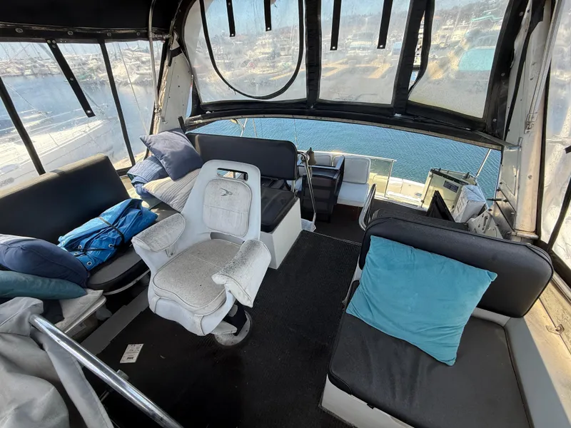 Slide: The Image of Interior of 1986 Kha Shing Nautique boat with seating and cushions, overlooking marina. - 13