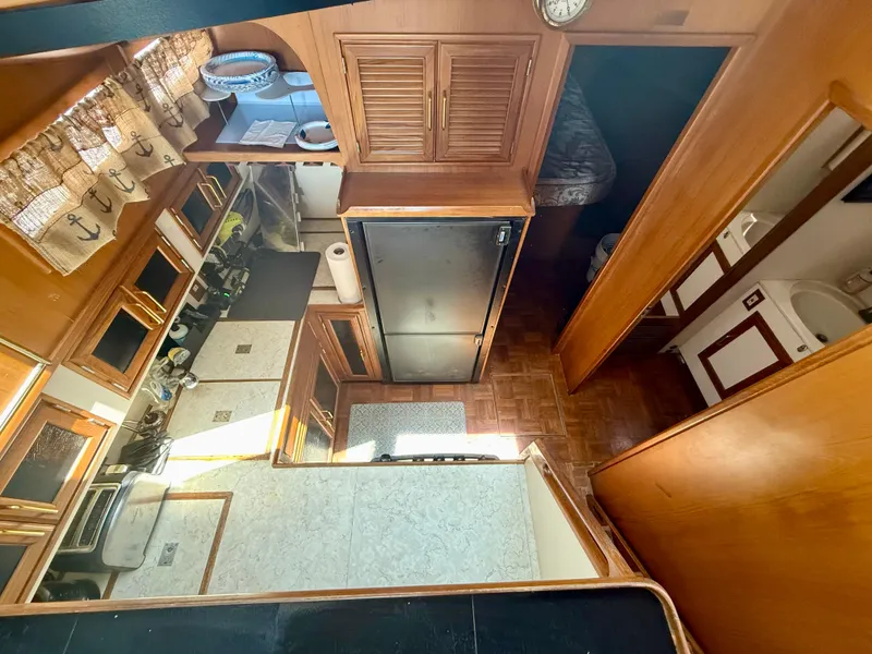 Slide: The Image of Interior of 1986 Kha Shing Nautique yacht, featuring kitchen and living area with wooden cabinetry. - 24