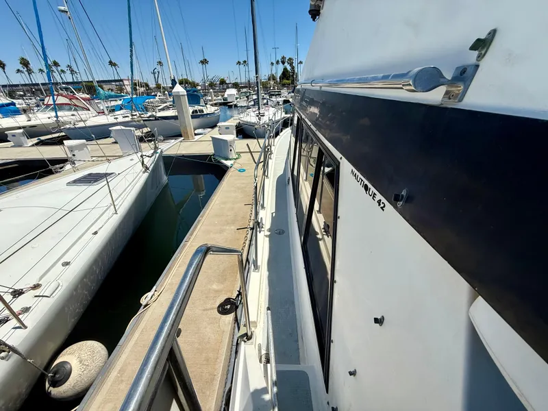 Slide: The Image of 1986 Kha Shing Nautique yacht docked at marina, surrounded by sailboats under clear blue sky. - 7