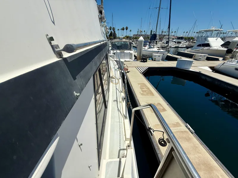Slide: The Image of 1986 Kha Shing Nautique yacht docked at a marina under clear blue skies. - 8