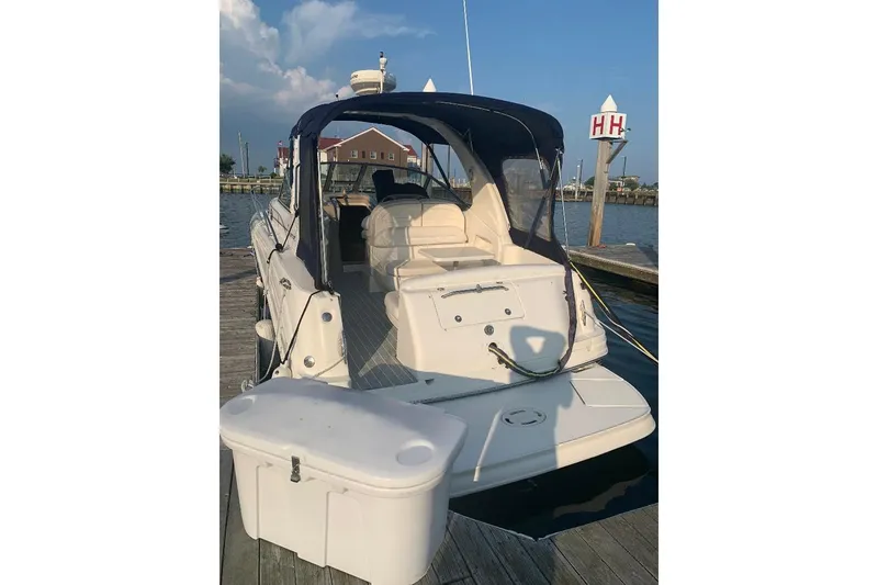 Slide: The Image of 2005 Sea Ray 300 Sundancer docked at marina, rear view with canopy and seating. - 12