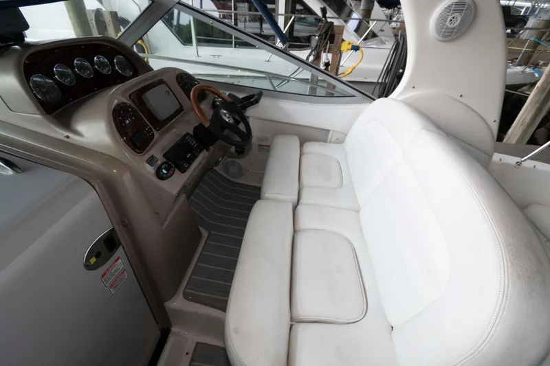 Slide: The Image of 2005 Sea Ray 300 Sundancer cockpit with white seating and control panel. - 13