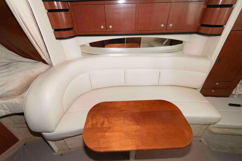 Slide: The Image of Luxurious interior of 2005 Sea Ray 300 Sundancer with white leather seating and wooden table. - 21