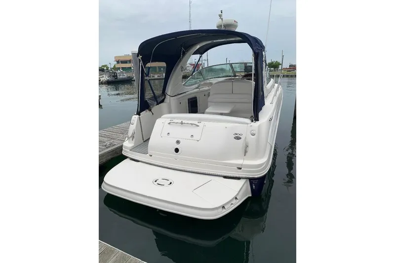 Slide: The Image of 2005 Sea Ray 300 Sundancer boat docked, featuring a sleek white exterior and blue canopy. - 6