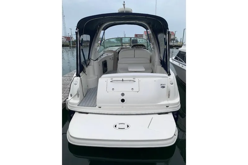 Slide: The Image of 2005 Sea Ray 300 Sundancer boat docked, rear view with open cockpit and swim platform. - 8